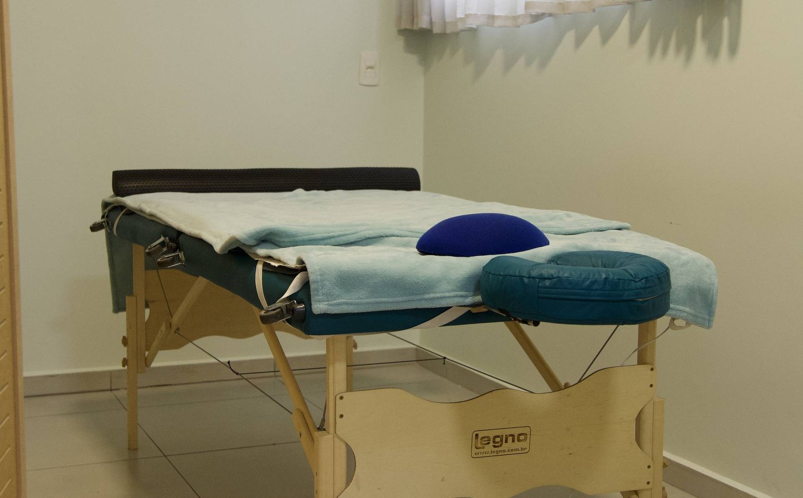 Sala de atendimento com maca preparada e luz natural