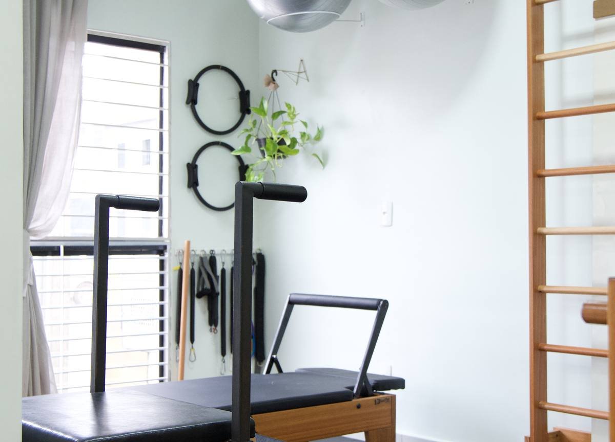 Studio de pilates com aparelhos de madeira e piso emborrachado